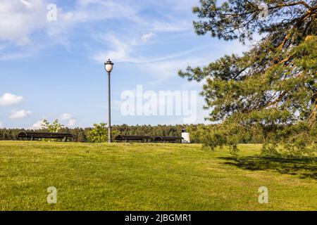 Panca di riposo e vecchia lampada moda nel parco della città Foto Stock
