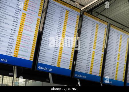 Imbarco per la partenza all'aeroporto Schiphol di Amsterdam. Molti ritardi sono visibili sui cartelli a causa di grandi folle e carenza di personale Foto Stock