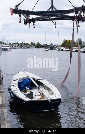 La barca a vela è stata appena sollevata dal molo in acqua da una gru. Gli pneumatici che si trovavano sotto la nave si stendono in acqua Foto Stock