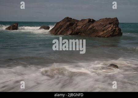 Immagine a lunga esposizione di onde che si infrangono sulle rocce della costa nord della Cornovaglia Foto Stock