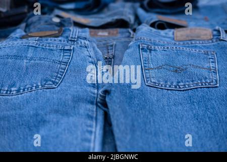 I jeans sono esposti in una stalla del mercato. Concentratevi sulle tasche dei pantaloni, i marchi sono sfocati. Immagine di sfondo Foto Stock