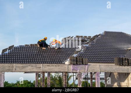 Lavoro di squadra di Un lavoratore di costruzione installare nuovo tetto, trapano elettrico usato su nuovi tetti con tegole di calcestruzzo, attrezzi di tetto. Fuoco selettivo di Conc Foto Stock