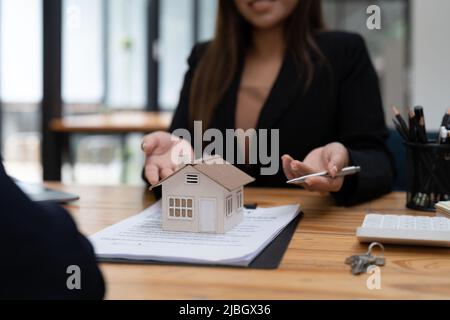 Agente immobiliare o ufficiale di banca descrive l'interesse di prestito al cliente con i contratti di acquisto della casa o sui prestiti di ufficio e sui tassi di interesse. Foto Stock