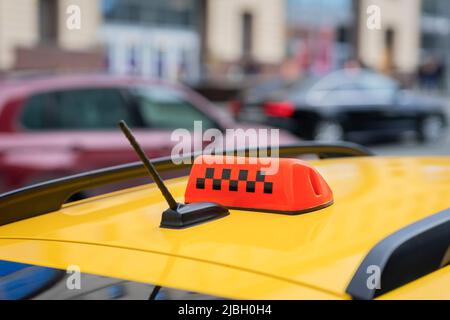 Primo piano del cartello taxi, simbolo sull'auto. Traffico offuscato astratto. Sfondo urbano moderno, fuoco selettivo Foto Stock