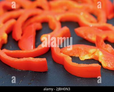 Primo piano di peperoni rossi affettati su griglia antiaderente, verdure sane per grigliare o friggere Foto Stock