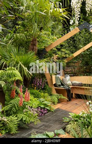 Un arco contemporaneo in legno e piattaforma da giorno circondato da lussureggianti piantagioni nel Kingston Maurward Space Within Garden progettato da Michelle Brown. Foto Stock