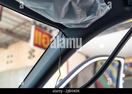 Installazione del cavo del registratore della videocamera o della videocamera nel telaio dell'auto presso l'officina del garage Foto Stock