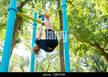 il ragazzo dello sport esegue un colpo di stato sul bar orizzontale del parco Foto Stock