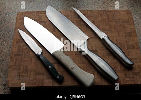 Un assortimento di coltelli da cucina diversi su un tagliere Foto Stock