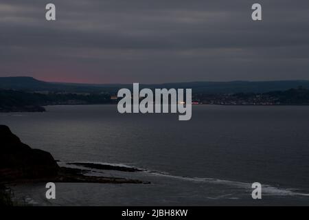 Vista di Scarborough al crepuscolo attraverso Scarborough Bay. Tratto dal Blue Dolphin Holiday Park, North Yorkshire, Regno Unito Foto Stock