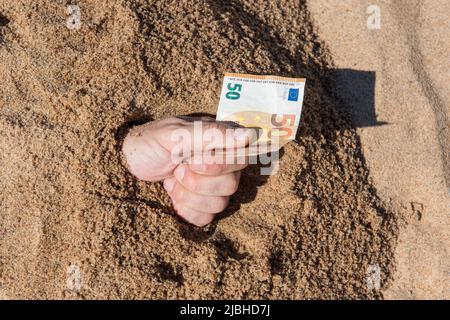 Cinquanta euro in mano di un uomo che si stacca dalla sabbia Foto Stock