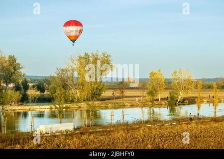 Coruche, Portogallo - 13 novembre 2021: Paesaggio fluviale di Sorraia a Coruche, Portogallo, con mongolfiera che vola sopra la linea di alberi della riva del fiume Foto Stock