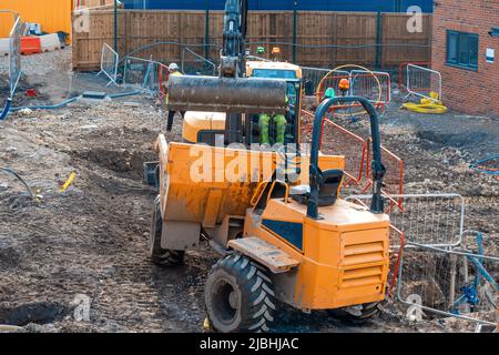 Impianti di costruzione e macchinari. Dumper ed escavatore che lavorano su cantiere di nuove case Foto Stock