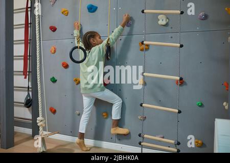 Ritratto di bambino nero attivo parete di arrampicata su casa sport set, copia spazio Foto Stock