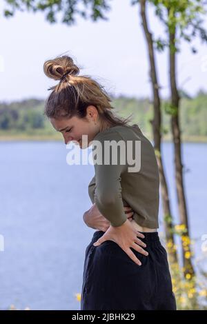 Persone, assistenza sanitaria e concetto di problema - donna che soffre di dolore alla schiena o ricci all'aperto. Foto di alta qualità Foto Stock