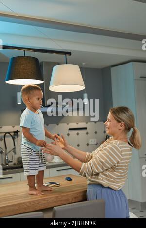 Ritratto di felice madre caucasica che gioca con ragazzo carino toddler in casa cucina interno Foto Stock