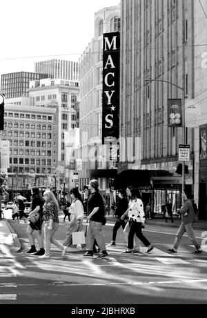 I pedoni attraversano una strada ad un incrocio trafficato di fronte ai grandi magazzini Macy's a San Francisco, California. Foto Stock