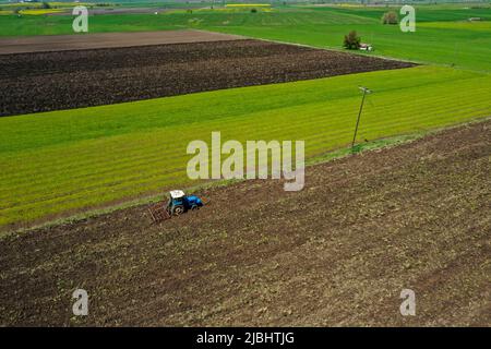 Vista aerea del trattore agricolo che aratura in campo, trattore che prepara in primavera il coltivatore a base di terreno seminato Foto Stock