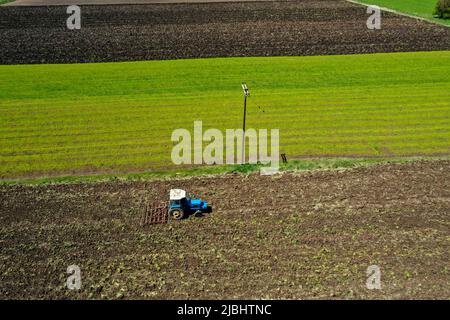 Vista aerea del trattore agricolo che aratura in campo, trattore che prepara in primavera il coltivatore a base di terreno seminato Foto Stock