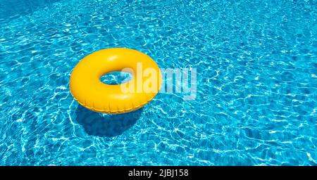 Anello giallo galleggiante nella piscina blu. Anello gonfiabile, concetto di riposo Foto Stock