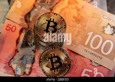 Toronto, Canada - Ottobre 30. 2021: Bitcoin su cinquanta e cento banconote in dollari canadesi. Cryptocurrency trading con denaro canadese Foto Stock