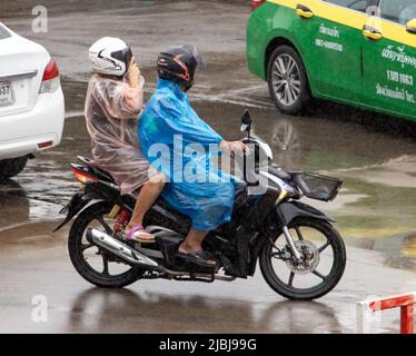 SAMUT PRAKAN, THAILANDIA, 03 2022 MARZO, una coppia con un impermeabile corre una moto sotto la pioggia Foto Stock