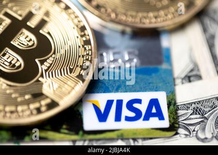 Bolzano, Italia - Aprile 10 2021: Bitcoin su carta di debito Visa e banconote da un dollaro. Denaro digitale con denaro plastico. Banconote come sfondo. Credito Foto Stock