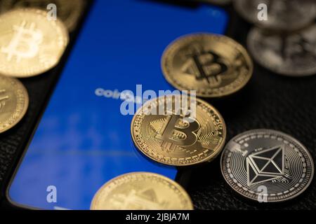 Bolzano, Italia - Aprile 10. 2021: Smartphone con applicazione coinbase circondata da monete d'oro bitcoin e d'argento etereo Foto Stock