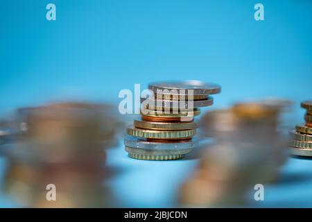 Accumulate monete in euro su sfondo blu. Spazio copia in alto. Moneta europea Foto Stock