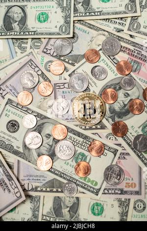 Bitcoin sulle banconote in dollari. Un conto di cento dollari accanto alla moneta di bitcoin d'oro e monete di dollari. Pennies a quarti dagli Stati Uniti. Concetto di scambio di crittografia Foto Stock