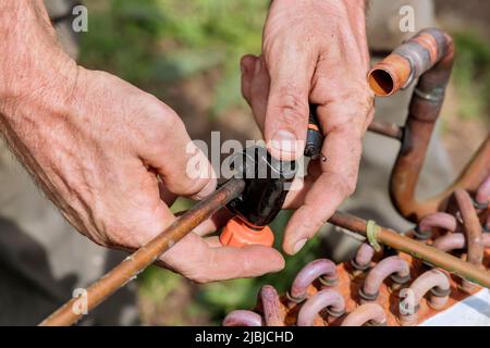 Utilizzare un tagliatubi per tagliare il tubo in rame all'esterno Foto Stock