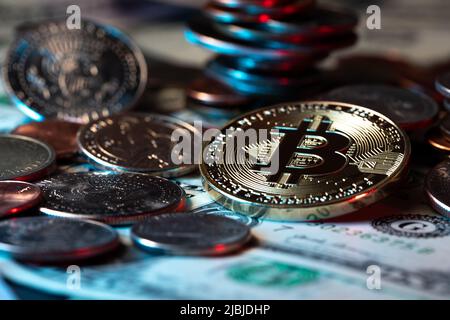 Bitcoin accanto alle monete e alle banconote in dollari. Valuta crittografica digitale con denaro contante in dollari USA. Cambio del dollaro con le valute cripto sopra la catena del blocco technolog Foto Stock