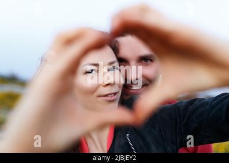 Coppia di mezza età sorridendo e facendo il cuore con le mani. Foto Stock