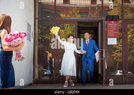 Kirov, RUSSIA - 10 agosto 2021: Sposi e sposi presso l'ufficio del registro dopo la cerimonia ufficiale del matrimonio e persone, amici, parenti, ospiti co Foto Stock