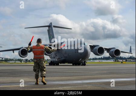 U.S. Air Force Tech. SGT. Nathan Martinez, un capo equipaggio assegnato al 446th Aircraft Maintenance Squadron marshalls a C-17 Globemaster III Aircraft, 4 giugno 2022, Joint base Lewis-McChord, Washington. Il team McChord ha lanciato una nave a quattro navi di C-17s a supporto dell'esercizio di Joint Forcble Entry presso il Nevada Test and Training Range della United States Air Force Weapons School. (STATI UNITI Air Force foto di Master Sgt. Heather Cozad Staley) Foto Stock