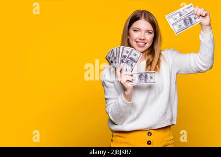 Ragazza di auto-fiducia che mostra fan dollari in contanti. Valuta cartacea. La donna sorridente prende diverse banconote da fan e sorride. Reddito passivo e ricchezza Foto Stock