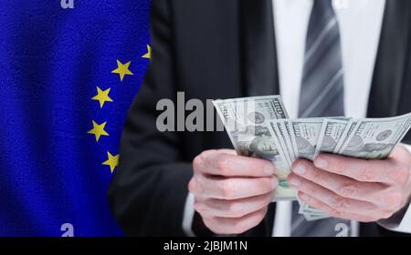 Le mani che detengono il denaro in dollari sulla bandiera dell'Unione europea Foto Stock