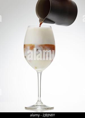 caffè espresso versato in un bicchiere di latte ghiacciato per preparare il cocktail Foto Stock