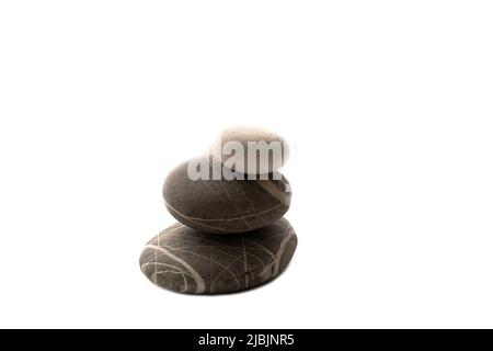 Una pila di pietre su uno sfondo bianco isolato .equilibrio e armonia. Copia foto spazio.orizzontale. Concetto di spa e assistenza sanitaria. Foto Stock