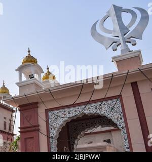 Khanda Sikh simbolo religioso santo all'entrata di gurudwara con l'immagine del cielo blu brillante è preso al SIS Ganj Sahib Gurudwara in Chandni Chowk di fronte Rosso Foto Stock