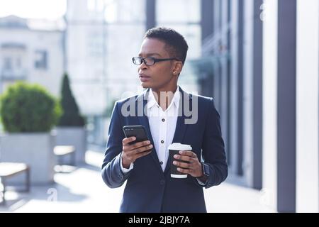 Donna d'affari che usa il cellulare, lavoratore afroamericano serio fuori ufficio Foto Stock
