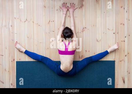 Giovane ragazza che esegue grandangolo seduta in avanti curva o upavistha konasana durante la lezione di stretching in palestra. Foto Stock