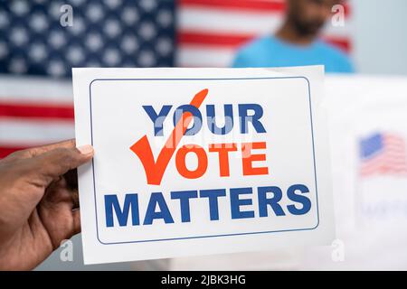 primo piano di mani che tengono la questione del voto di fronte al voto o stazione di voto - concetto di responsabilità e campagna. Foto Stock