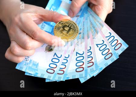 Bitcoin e russo rubli in mani femminili. Moneta decentralizzata elettronica, tasso di cambio e crescita della cripto-valuta Foto Stock