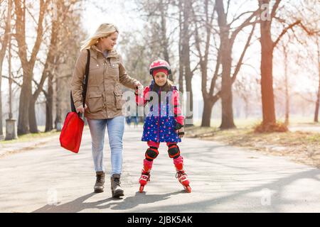 Madre e sua figlia che indossano pattini a rotelle nel parco Foto Stock