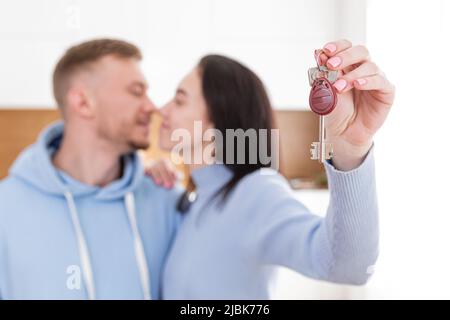 Ritratto di una giovane coppia, di un uomo e di una donna che si trasferirono in un nuovo appartamento. Casa, tenere le chiavi, abbracciando, sorridendo Foto Stock