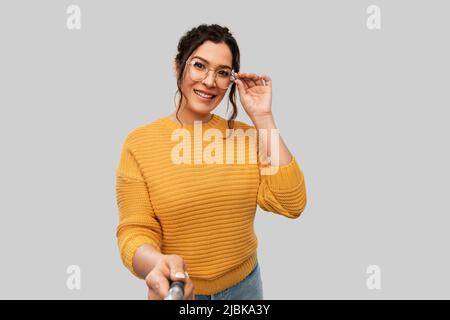 donna sorridente che fotografa con il bastone selfie Foto Stock