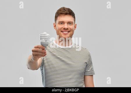 uomo giovane sorridente che tiene la lampadina Foto Stock