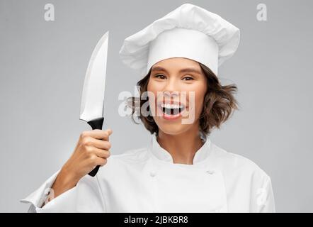 chef femminile sorridente in toque con coltello da cucina Foto Stock