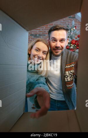 Giovane bella coppia felice gioiosamente aprire pacchetti di scatole con regali per Capodanno e Natale in amore e felice Foto Stock